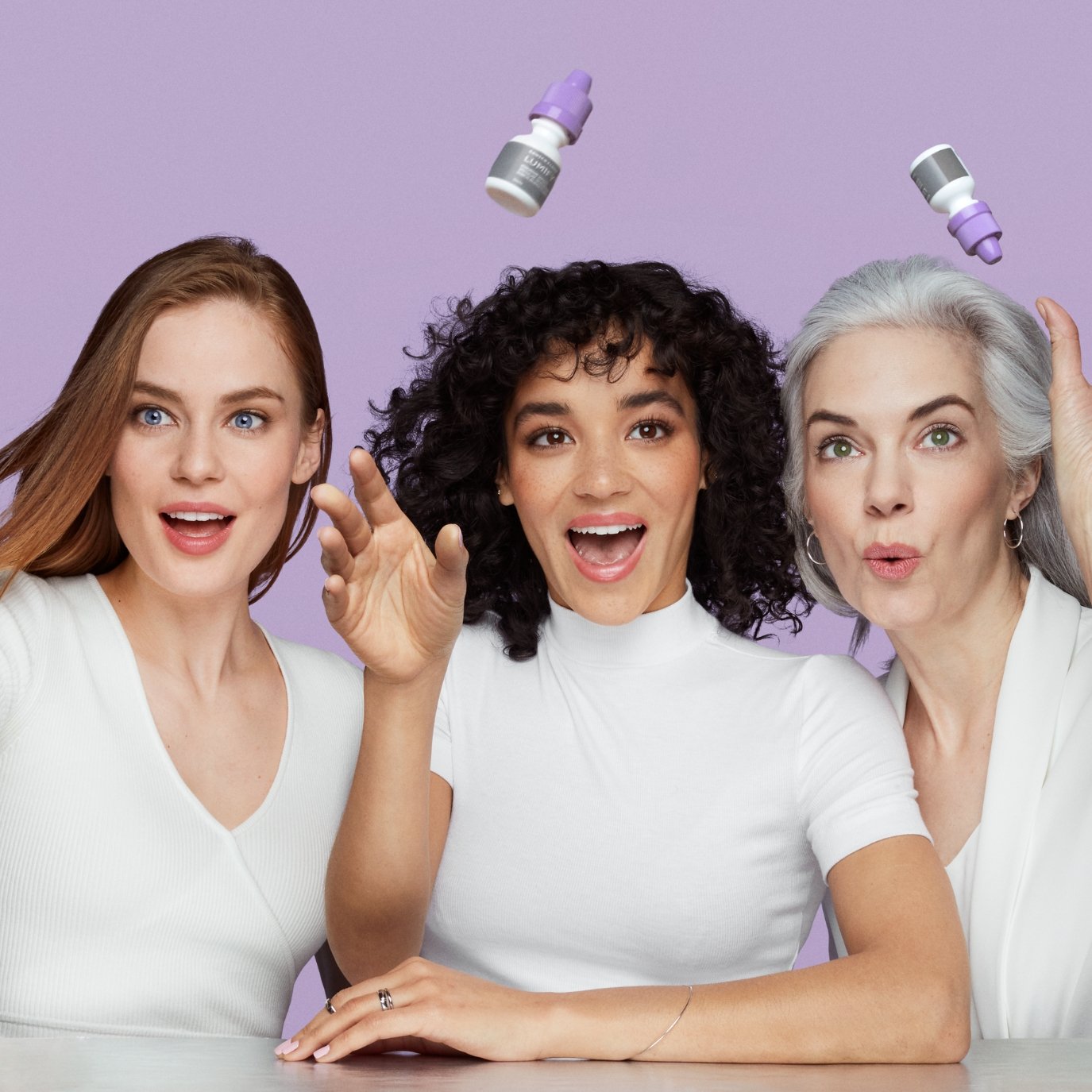 Three women standing next to each other trying to catch falling Lumify products